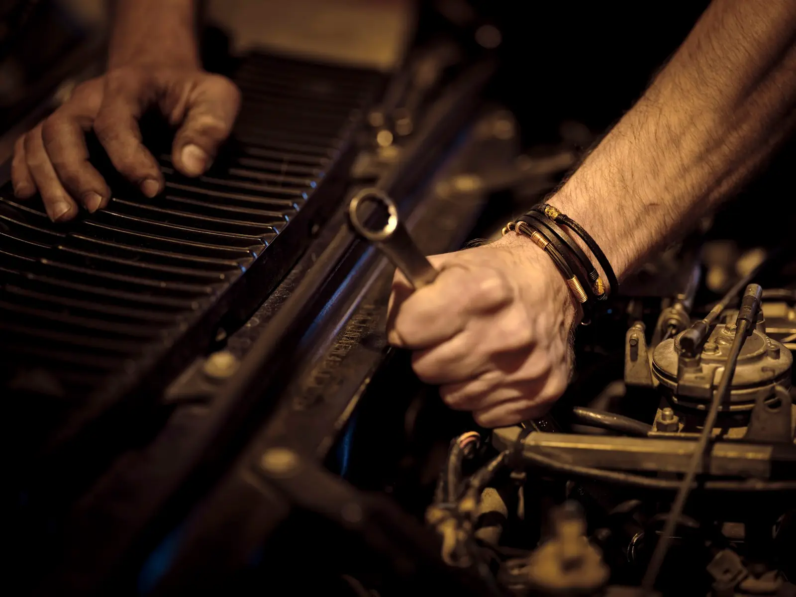 Hands turning a wrench deep in an engine bay