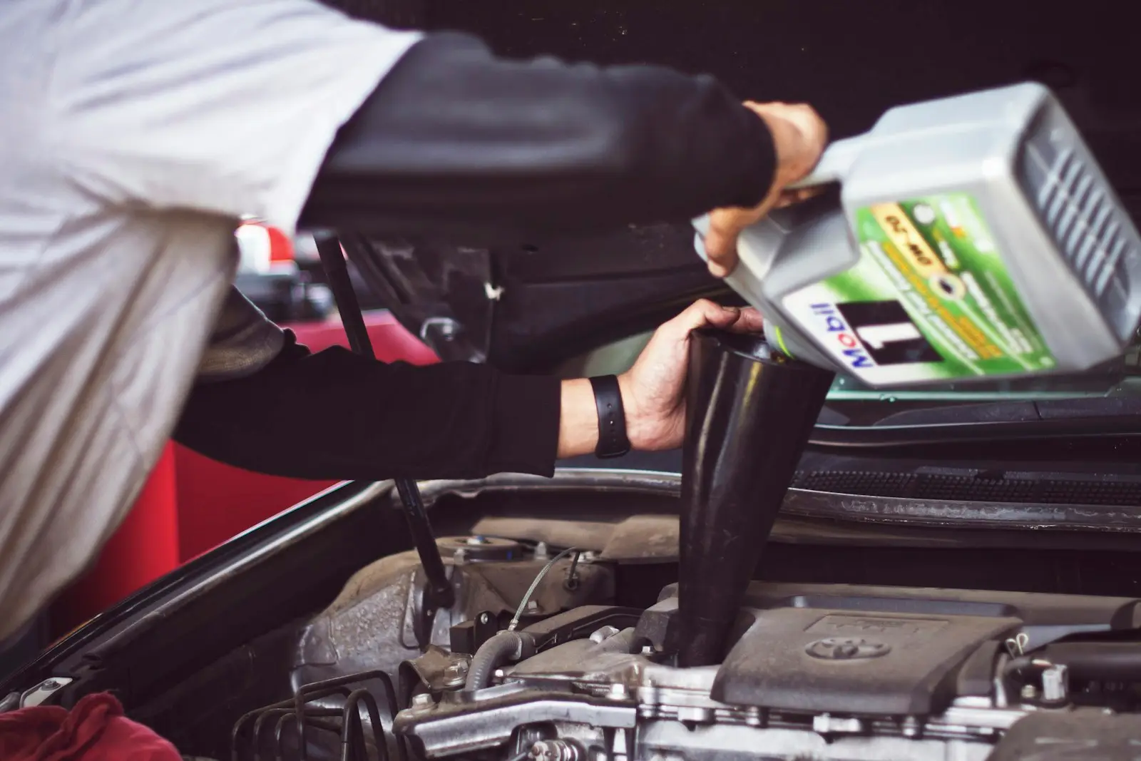 Technician pouring full synthetic oil into an engine