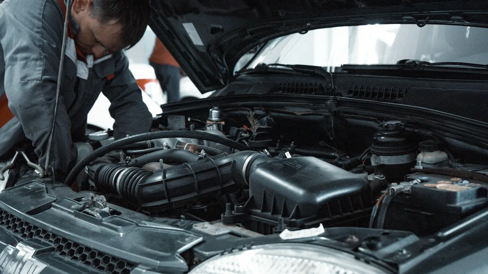 Technician checking hoses under an open hood